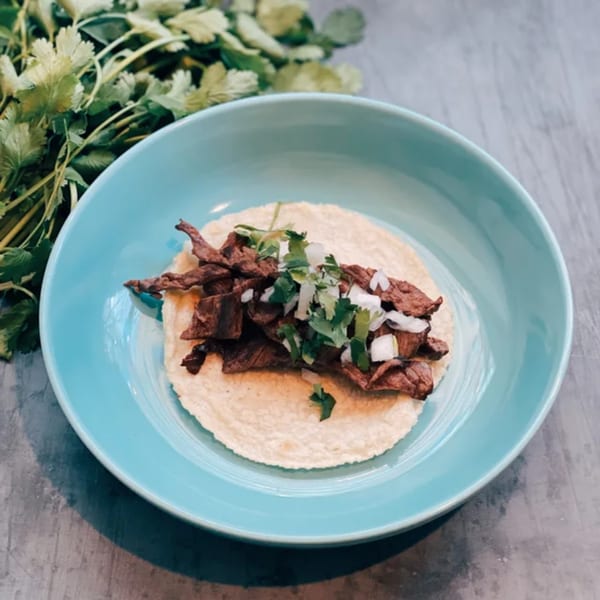 A single Sullivan Taqueria carne asada taco with cilantro and onions in a blue bowl.
